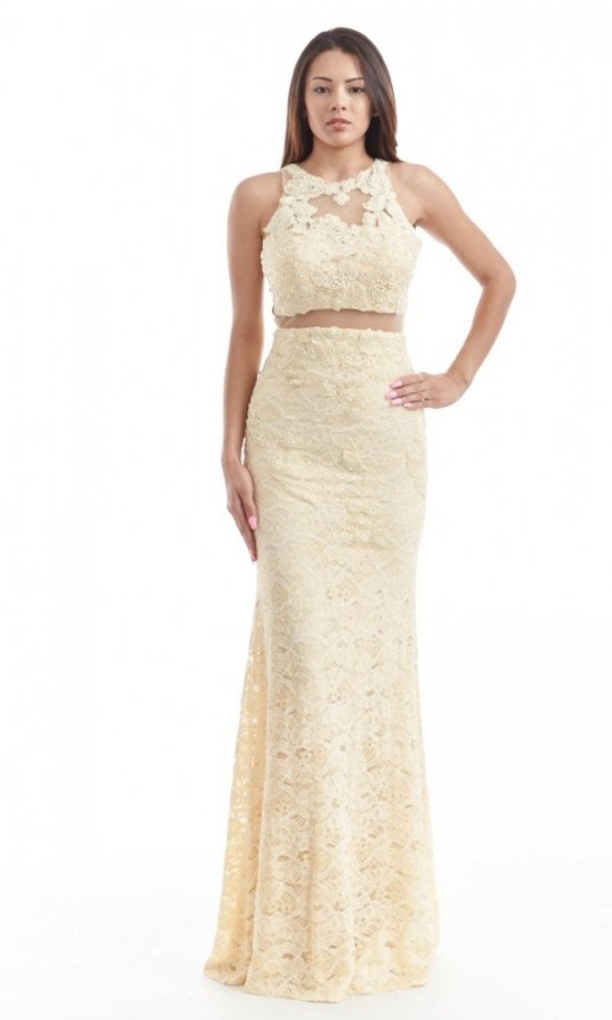 A woman wears the Chicas CR4225 Mock Two-Piece Long Lace Prom Dress—a sleeveless, cream, floor-length ensemble with embroidered lace, featuring a fitted skirt and crop top.